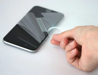 スマートフォン画面の保護フィルムを剥がす様子の写真